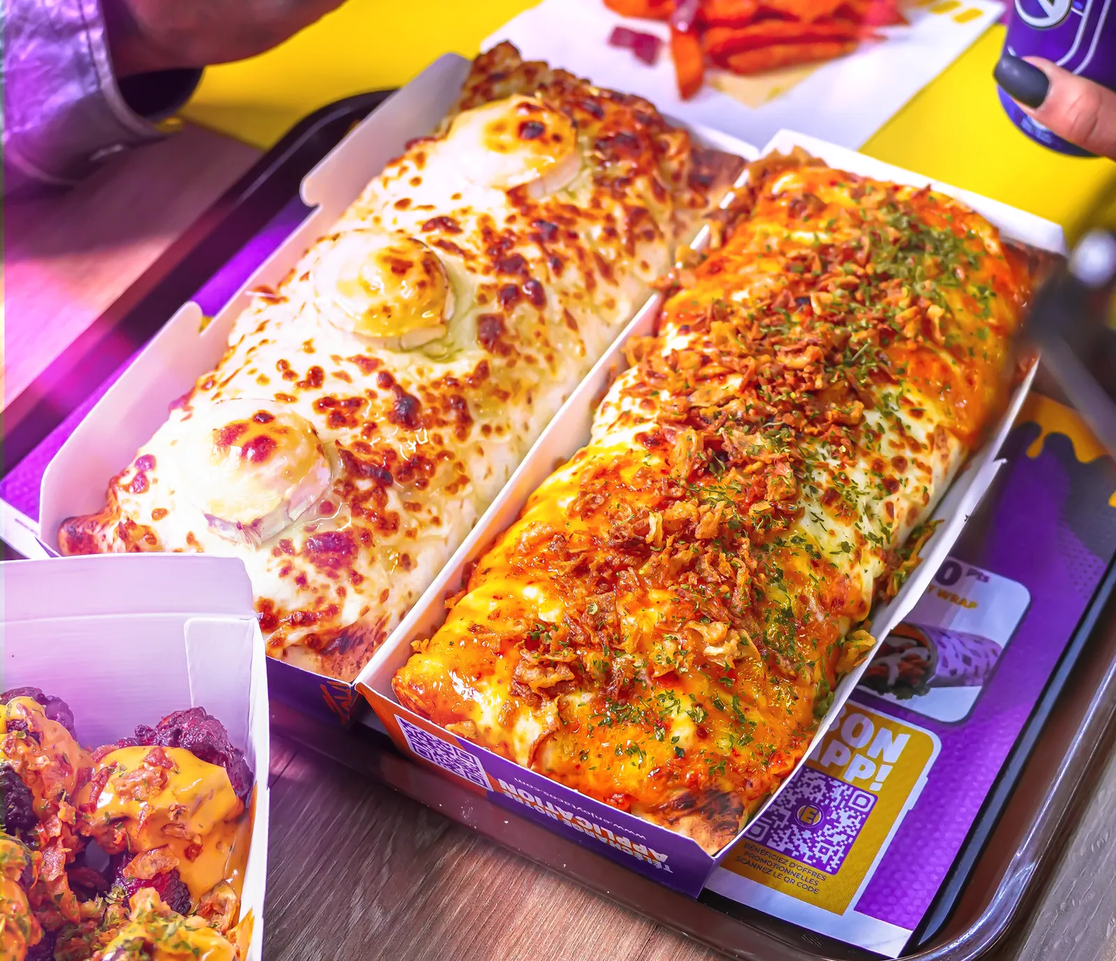 Deux tacos gratinés, fromage fondu et oignons frits, servis en barquette sur un plateau Enjoy avec des frites de patate douce